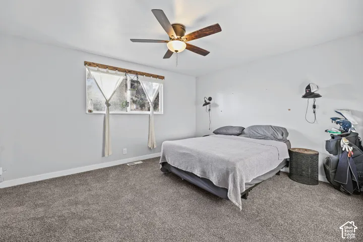 Spacious room with gray carpet, a window, and a ceiling fan with integrated lighting