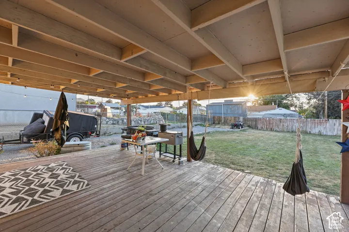 Expansive covered deck with exposed beam ceiling, string lighting, and wood-finish decking