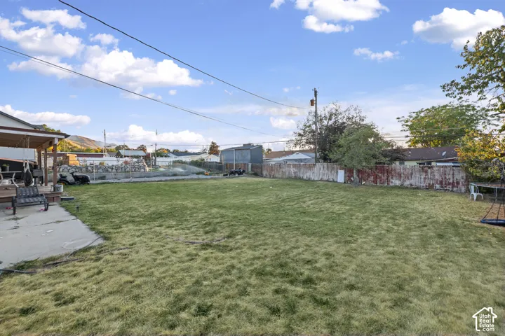 Expansive grassy yard with a concrete patio and a covered porch