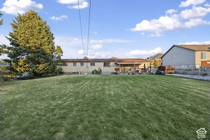 Expansive lawn with mature trees and a covered patio with a wood deck