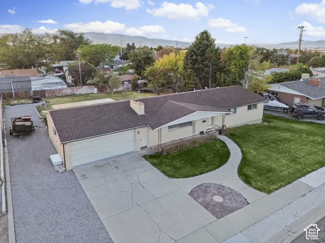 Single-story residence with a beige brick exterior, attached garage, concrete driveway, and a front lawn