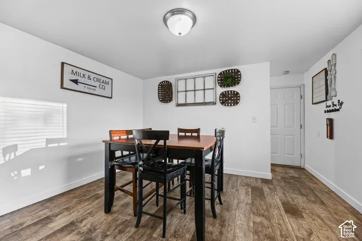 Wood-finish flooring, white painted walls, ceiling-mounted light fixture, and a white interior door