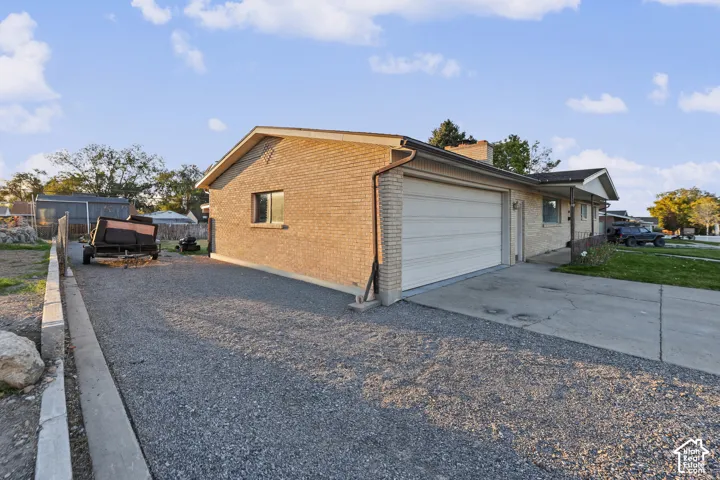 Single-story brick exterior, attached garage, and a gravel side yard