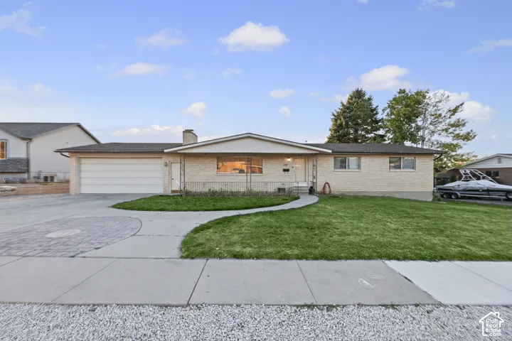 Single-story residence featuring a brick exterior, attached two-car garage, and a semicircular paver driveway