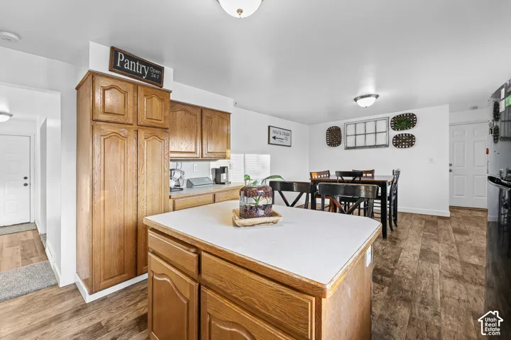 Wood-finish flooring throughout, white walls, and a kitchen island with a light-colored countertop