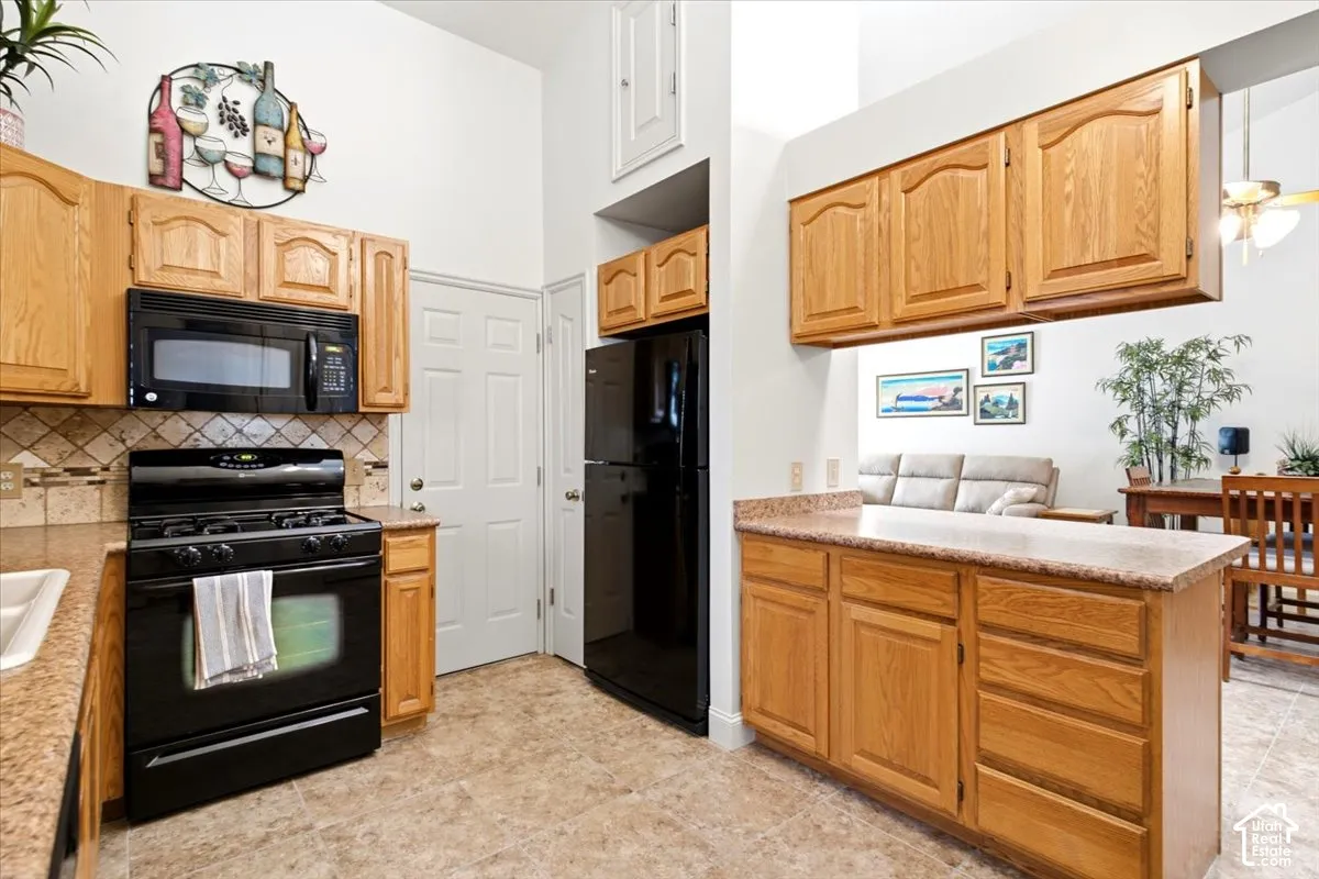 Kitchen featuring wood cabinetry, black appliances, tile flooring, and a pass-through window to an adjacent room