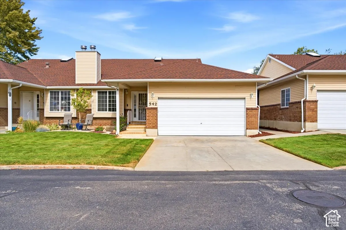 Attached single-family residence featuring a two-car garage, brick and siding exterior, front lawn, and concrete driveway