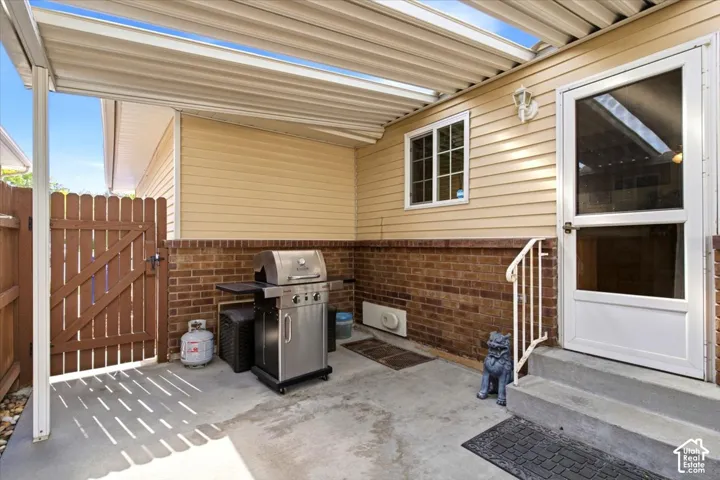 Covered patio with concrete flooring, brick wainscoting, and a privacy fence
