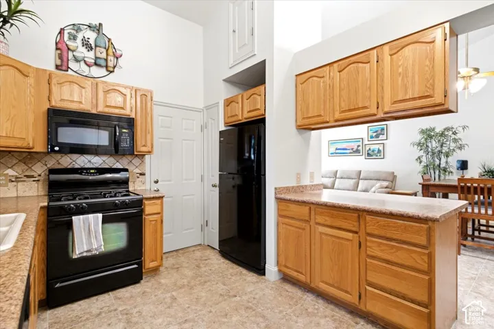 Kitchen featuring wood cabinetry, black appliances, tile flooring, and a pass-through window to an adjacent room