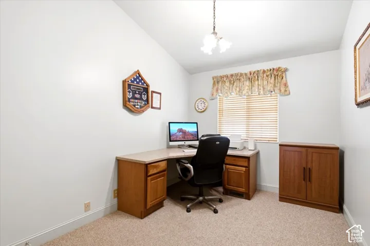 Vaulted ceiling, built-in desk with wood-finish cabinetry, window with blinds, carpeted flooring, and a ceiling-mounted light fixture
