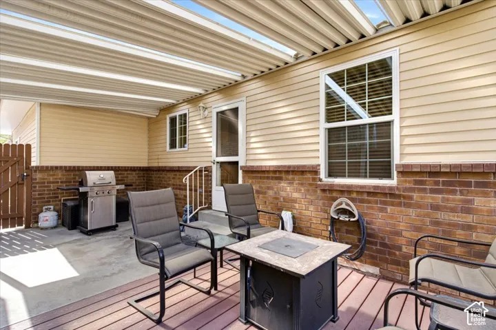 Covered patio featuring a slatted roof, brick wainscoting, and wood-finish decking