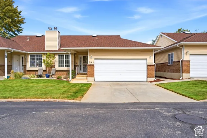 Attached single-family residence featuring a two-car garage, brick and siding exterior, front lawn, and concrete driveway