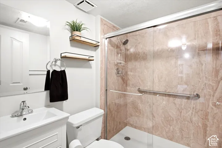 Shower enclosure with sliding glass door, integrated grab bar, and stone-finish wall panels