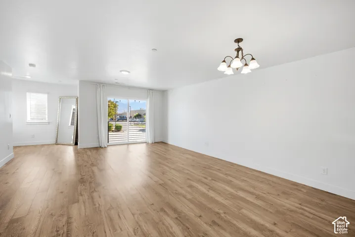 Wood-finish flooring, white walls, sliding glass door, recessed lighting, and a multi-arm chandelier