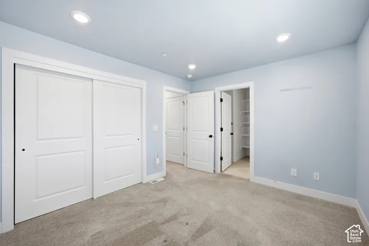 Recessed lighting, light-toned carpeting, white trim, and a white sliding panel closet door