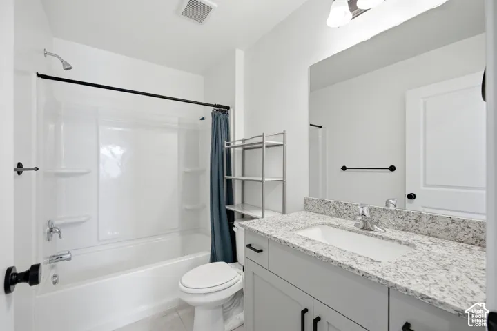 White vanity with a light speckled countertop and a single basin sink