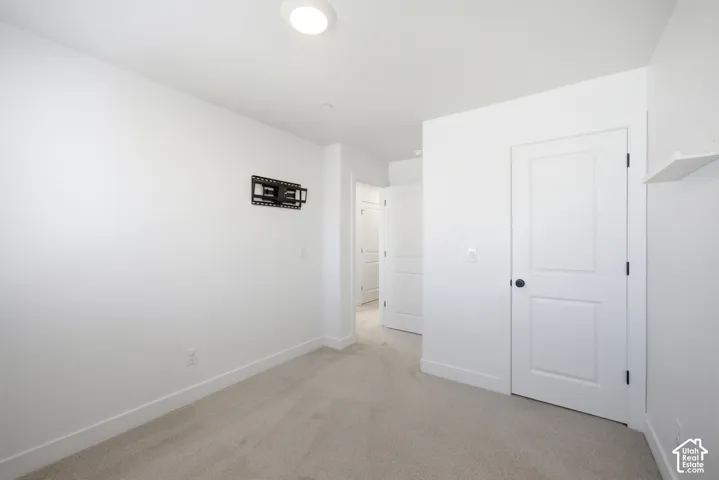 Recessed ceiling light, neutral wall paint, carpet flooring, wall-mounted bracket, and white interior doors