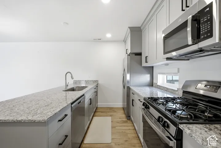 Granite countertops, stainless steel appliances, light gray cabinetry, wood-finish flooring, and recessed lighting