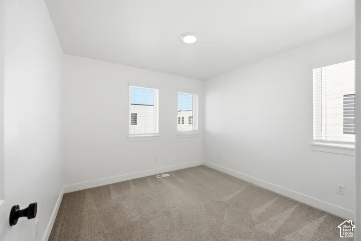 Recessed ceiling light, neutral-toned carpet, white walls, multiple windows with blinds, and white trim