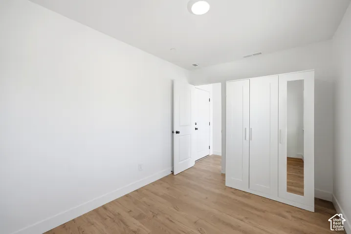 Crisp white walls, wood-finish flooring, recessed ceiling light, and white interior doors with black hardware