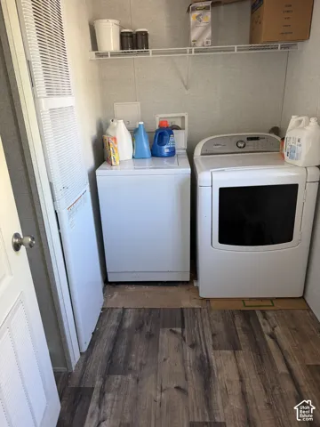 Dedicated laundry area featuring a washer and dryer, wire shelving, and wood-finish flooring