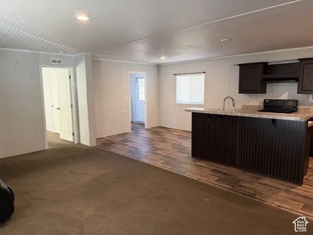 Open-concept living area with wood-finish flooring, recessed lighting, and a kitchen island with dark cabinetry