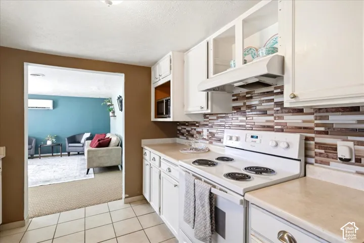 Kitchen featuring white cabinetry, tile backsplash, built-in range, and a microwave