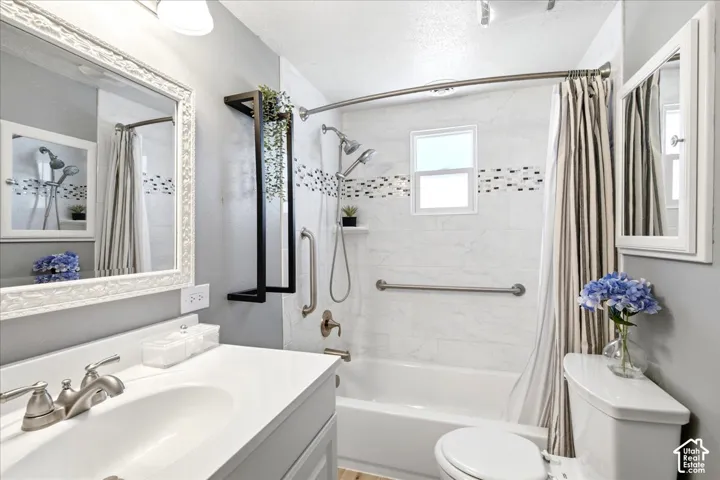 White vanity with a brushed nickel faucet, large ornate mirror, and light gray walls
