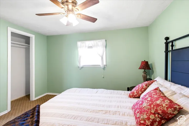 Bedroom featuring light green walls, a ceiling fan with light fixture, and a window with white trim