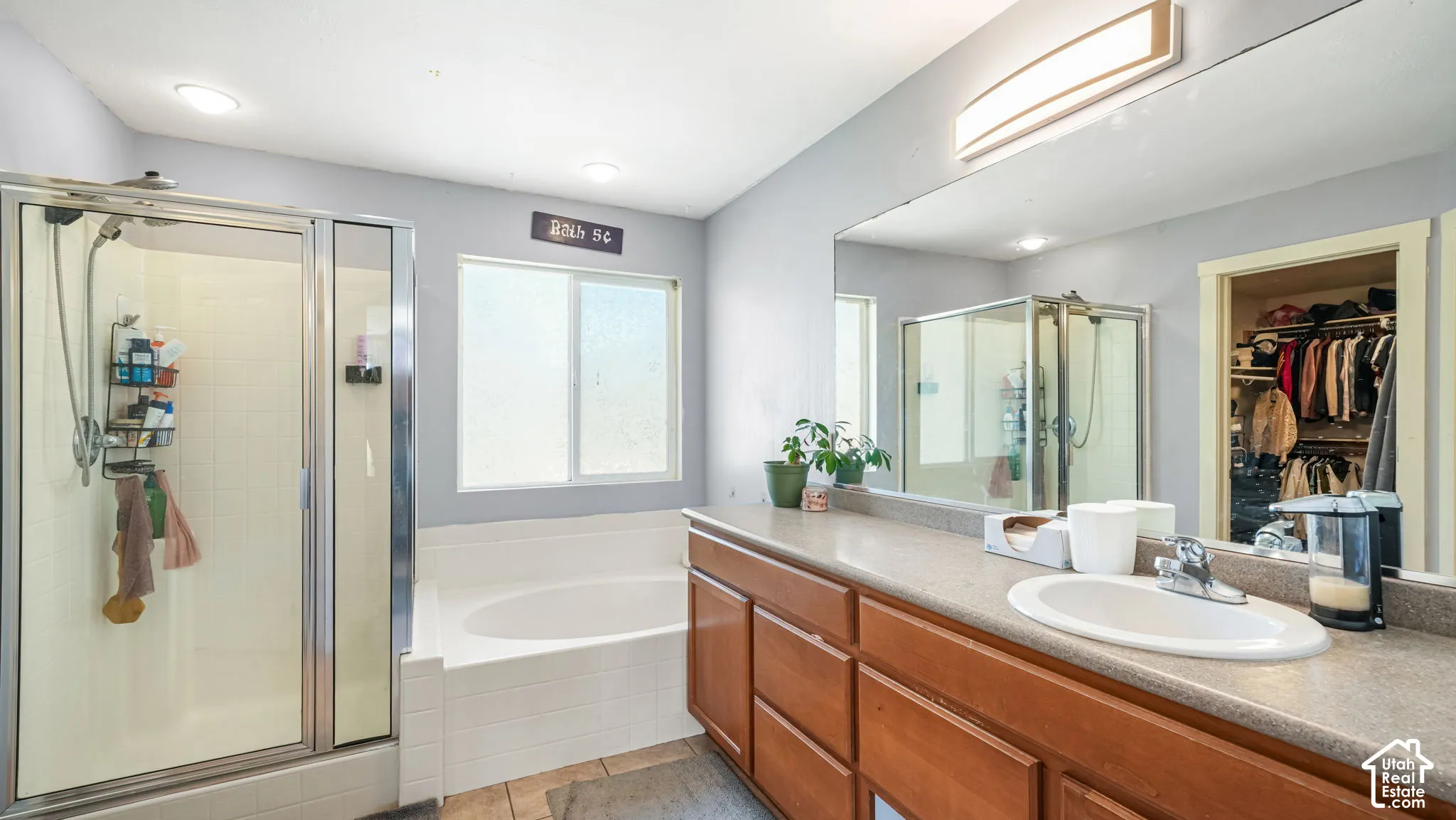 Double vanity with wood-finish cabinetry, built-in soaking tub, and glass-enclosed shower