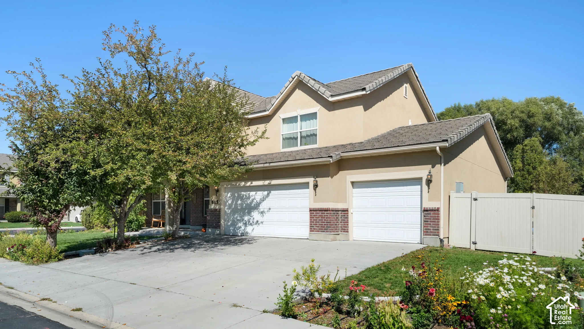 Stucco exterior with brick detailing, asphalt shingle roof, two-car garage, and a privacy fence