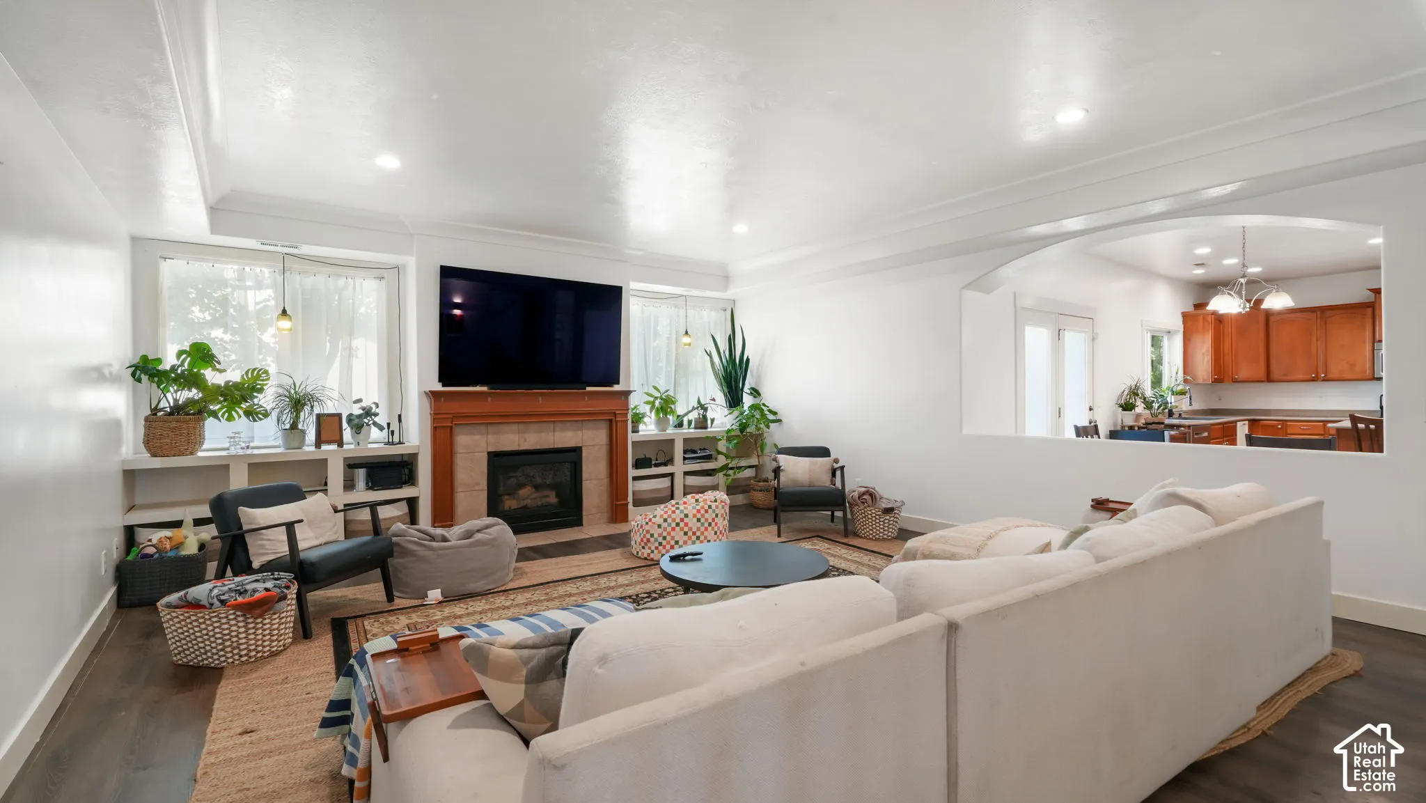 Living area featuring wood-finish flooring, a fireplace with a wood mantel, built-in shelving, and recessed lighting