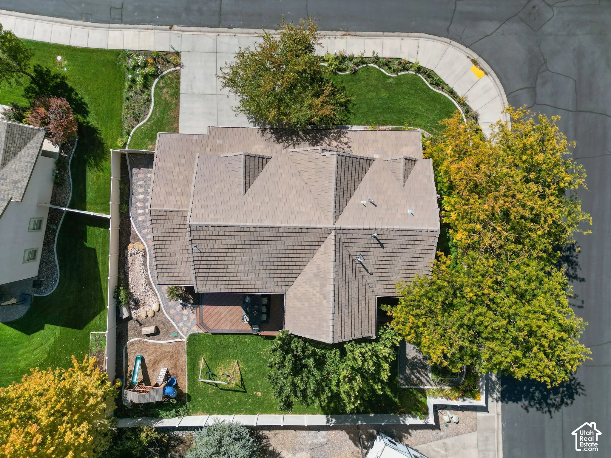 Pitched roofline, paved patio, mature trees, landscaped perimeter, and concrete pathways