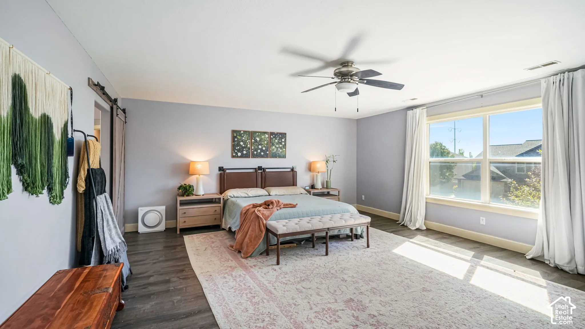 Expansive room with large windows, wood-finish flooring, and a ceiling fan