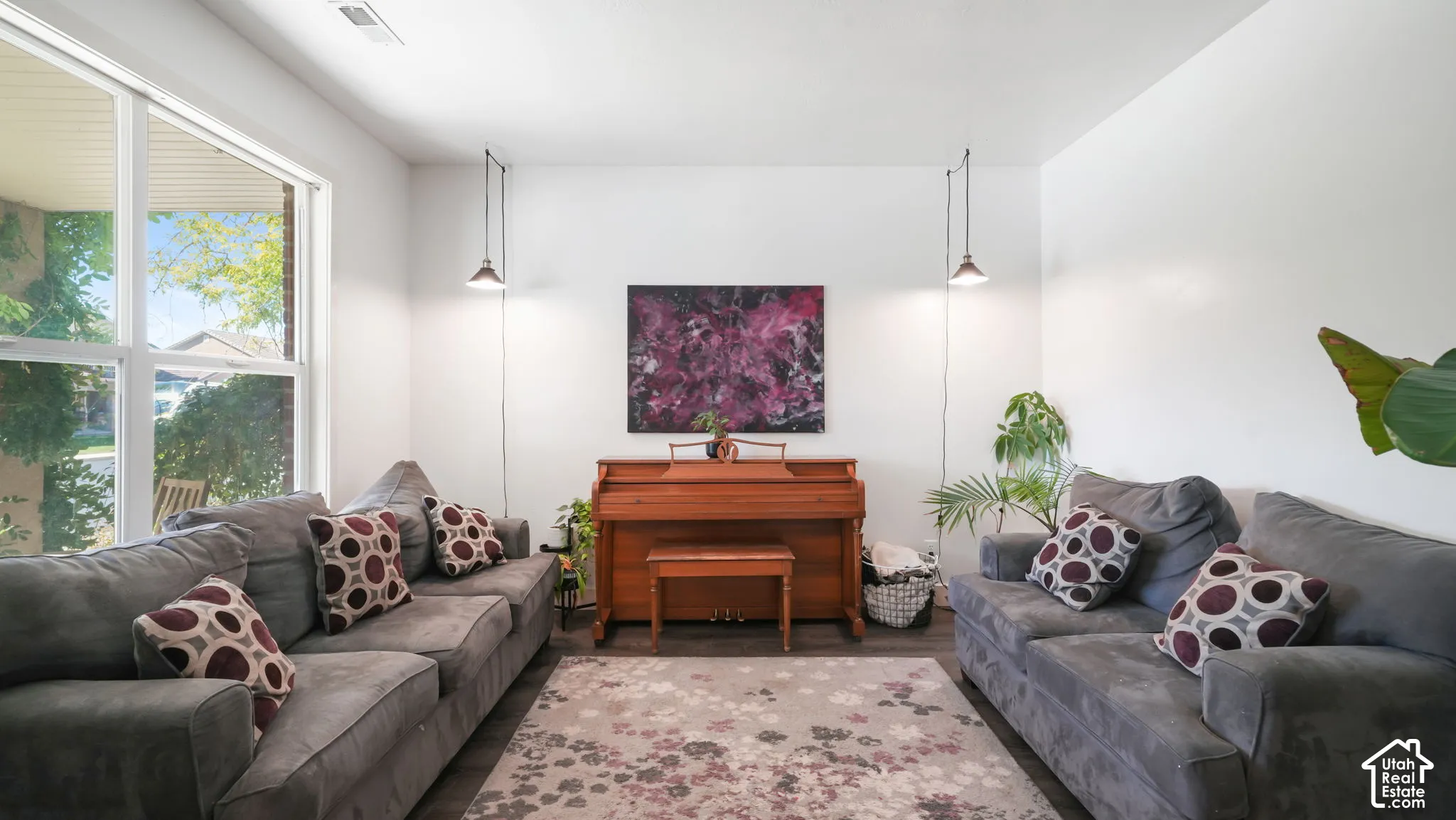 Spacious living area featuring large windows, wood-finish flooring, and crisp white walls