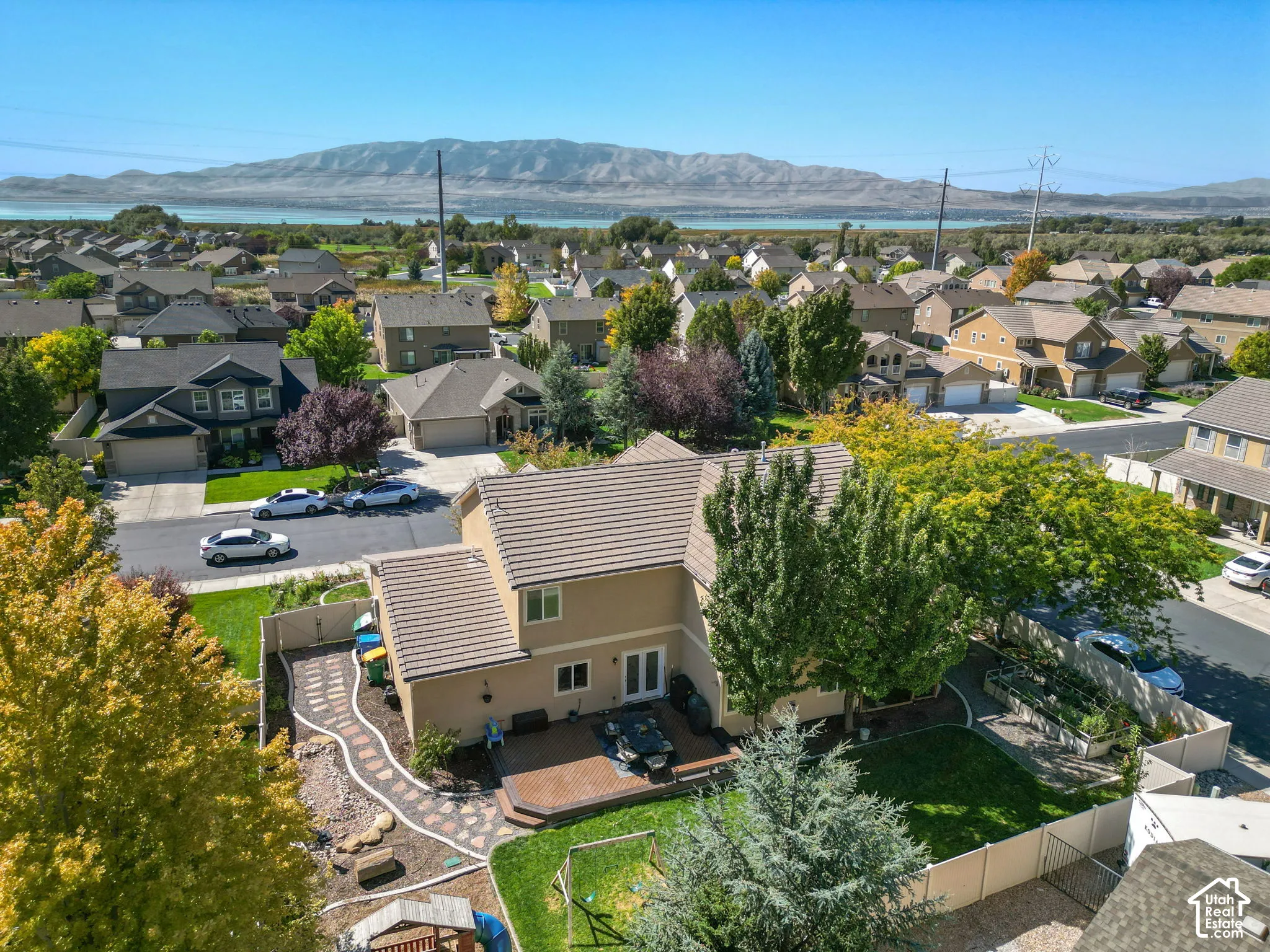 Aerial perspective showcasing the property with surrounding residences, mature trees, and a distant body of water