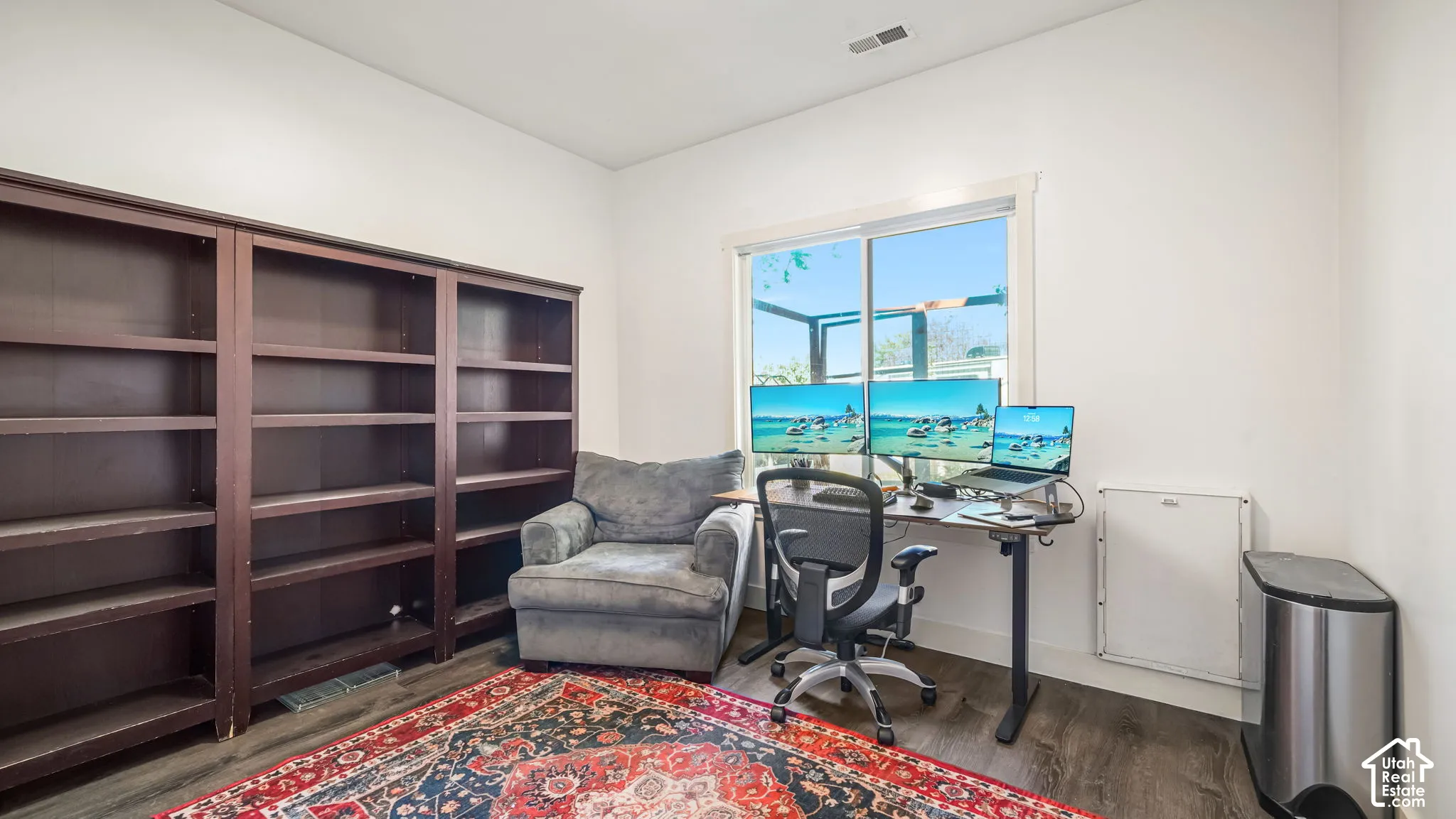 Wood-finish flooring, built-in shelving, white walls, and a large window