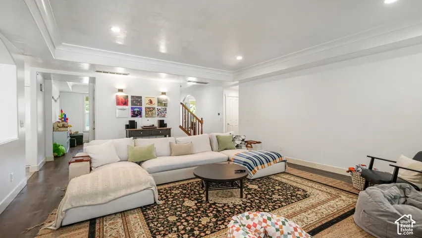 Recessed ceiling lighting, dark wood-finish flooring, decorative wall sconces, and crown molding