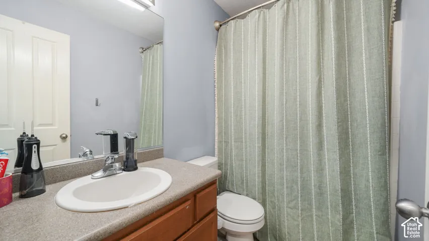 Bathroom featuring a single vanity with a laminate countertop, an oval undermount sink, and a chrome faucet