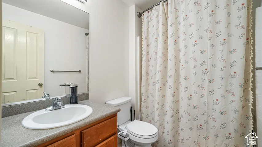 White vanity with a neutral countertop, undermount sink, and chrome faucet