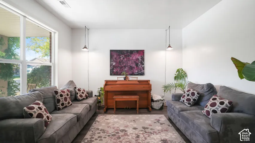Spacious living area featuring large windows, wood-finish flooring, and crisp white walls