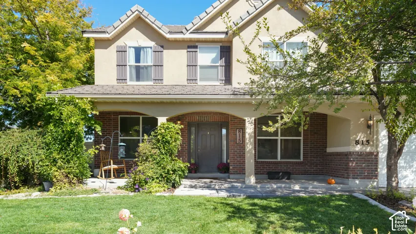 Stucco exterior with brick accents, covered front porch, arched entryway, gabled roofline, and attached garage