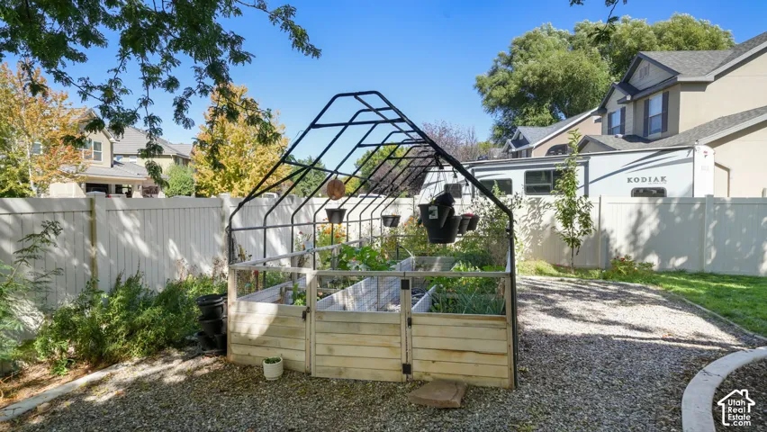 Backyard features a gravel path, raised garden beds, and a white privacy fence