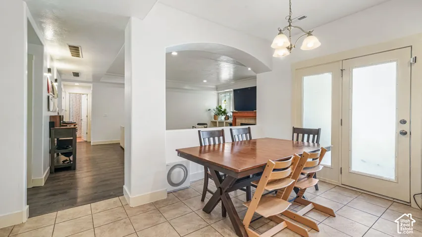 Dining area with tile flooring, a chandelier, and double glass doors