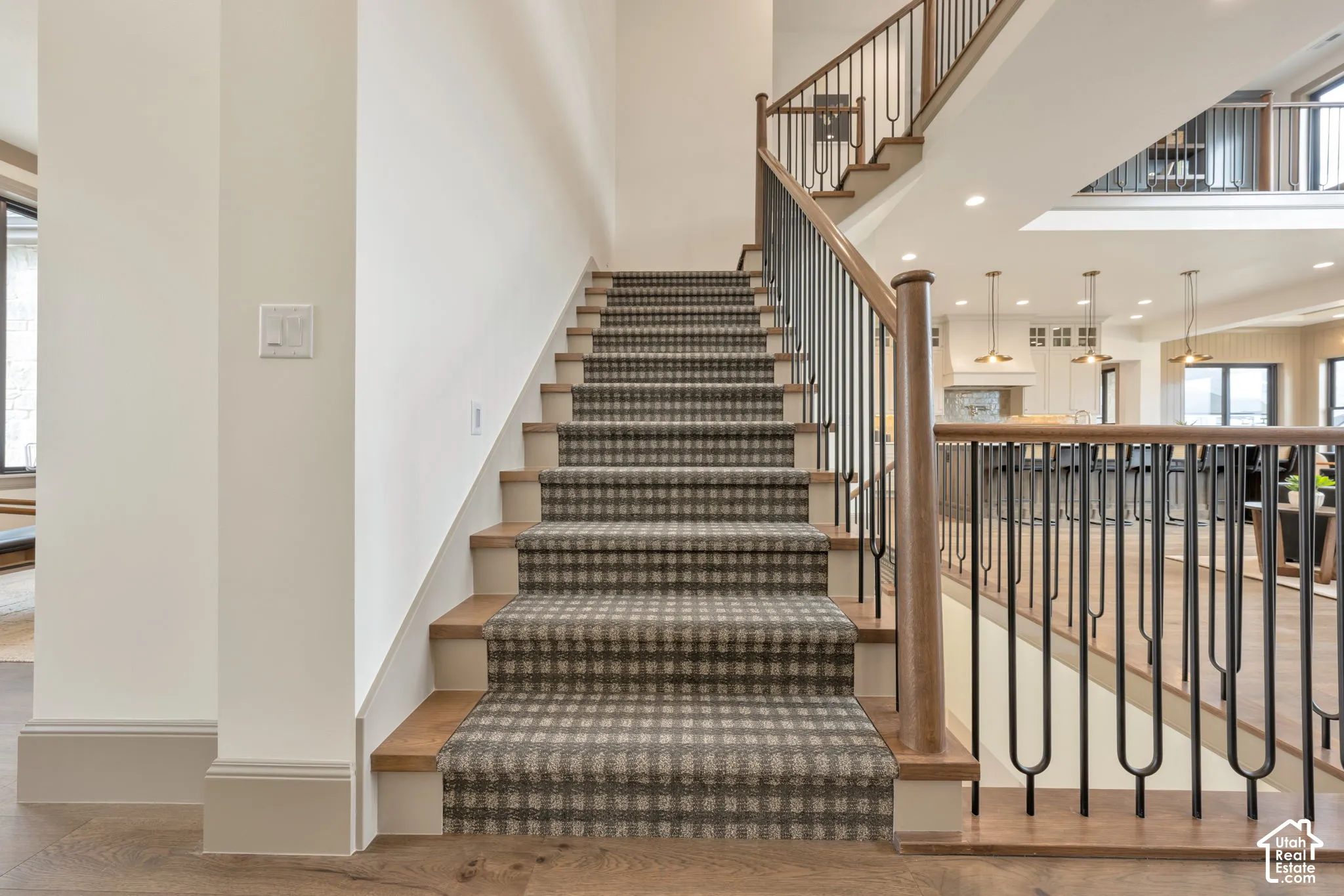 Staircase featuring wood treads, patterned runner, and iron balusters with wood handrails