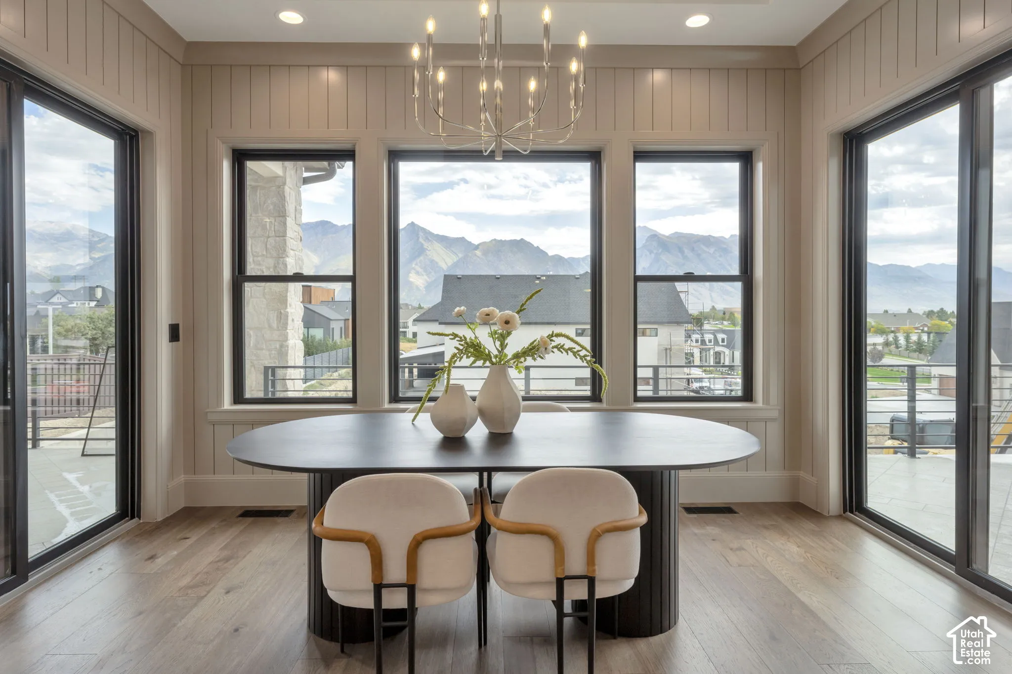 Wood-finish flooring with vertical paneling accent walls, framed by multiple windows and sliding glass doors