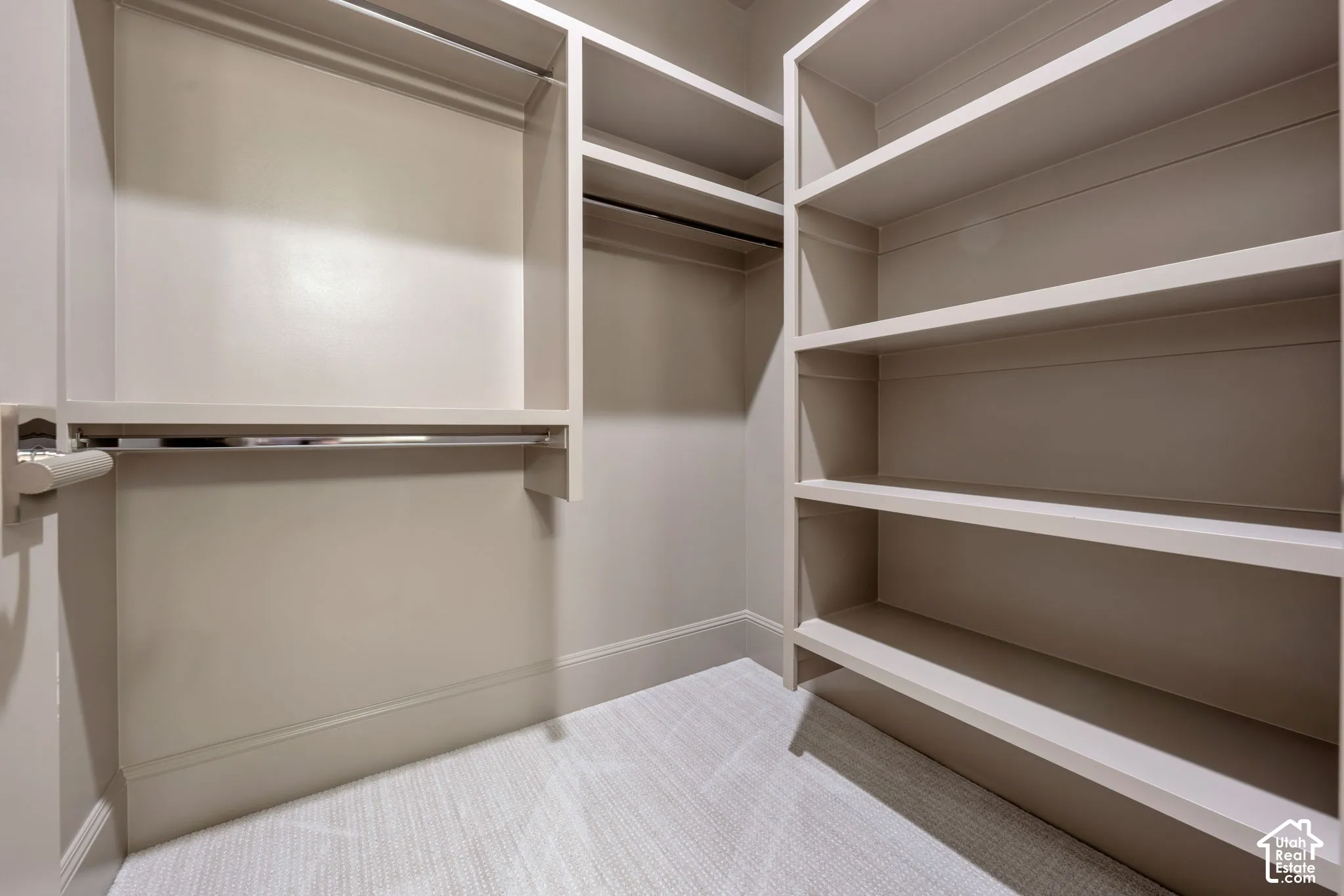 Built-in shelving, multiple hanging rods, and light-toned carpet flooring