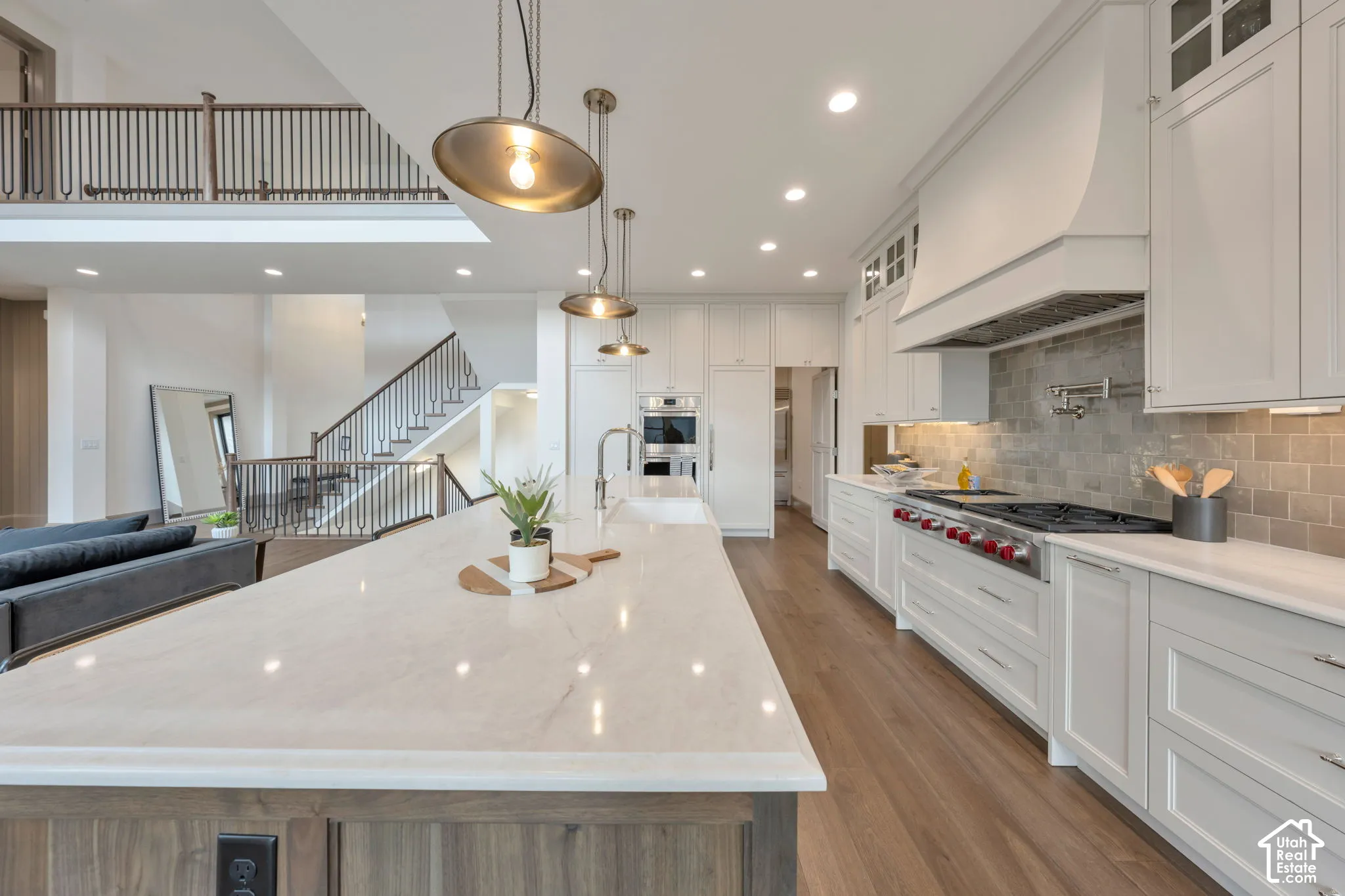 Spacious kitchen featuring a large island with a countertop, wood-finish flooring, and white cabinetry
