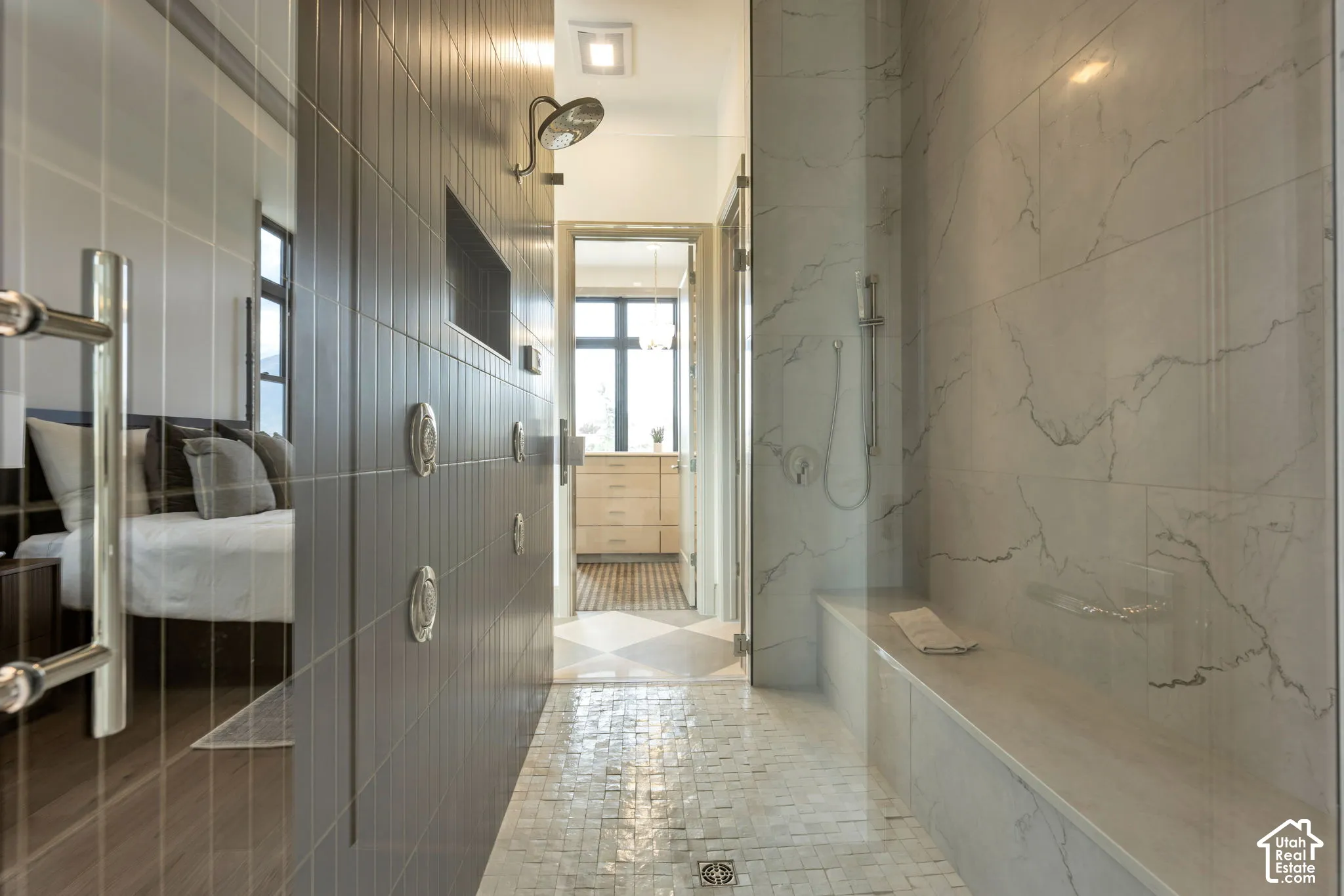 Spacious shower with mosaic tile flooring, a built-in bench, ceiling-mounted showerhead, and a handheld shower fixture