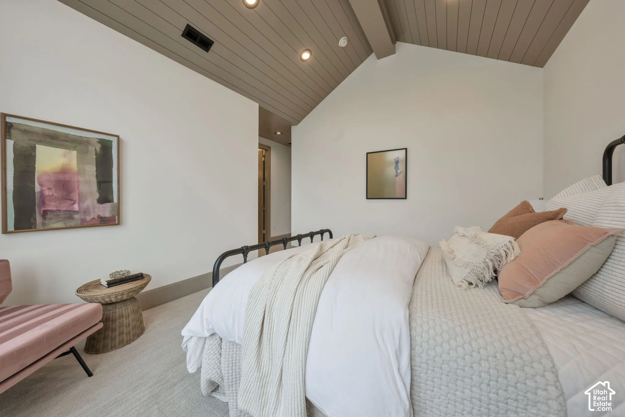 Vaulted wood-paneled ceiling with exposed beams, recessed lighting, wall-to-wall carpeting, and a black metal bed frame